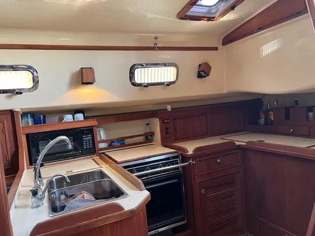  Yacht Photos Pics Interior of 1999 Island Packet 380 sailboat kitchen with wood cabinetry and appliances.
