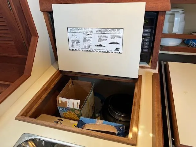  Yacht Photos Pics Storage compartment in a 1999 Island Packet 380 sailboat galley, with food items and a microwave.