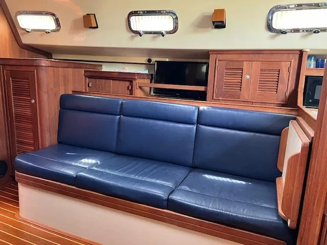  Yacht Photos Pics Interior of 1999 Island Packet 380 sailboat with blue leather seating and wooden cabinetry.