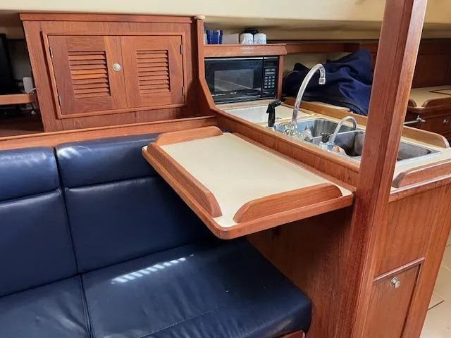  Yacht Photos Pics Interior of 1999 Island Packet 380 sailboat with wooden cabinetry, blue seating, and kitchenette.