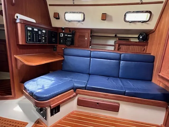  Yacht Photos Pics Interior of 1999 Island Packet 380 sailboat with blue cushioned seating and wooden accents.