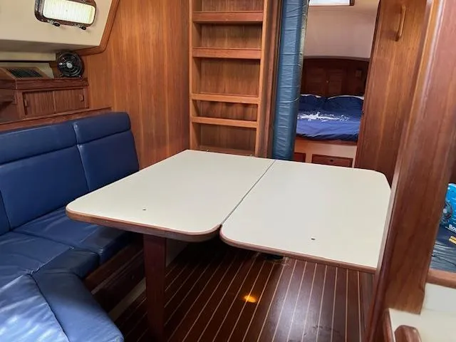  Yacht Photos Pics 1999 Island Packet 380 interior with wooden finish, blue seating, and foldable table.