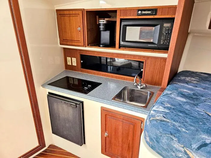  Yacht Photos Pics Compact kitchen in 2001 Carolina Classic Express 35 boat with microwave, sink, and stove.