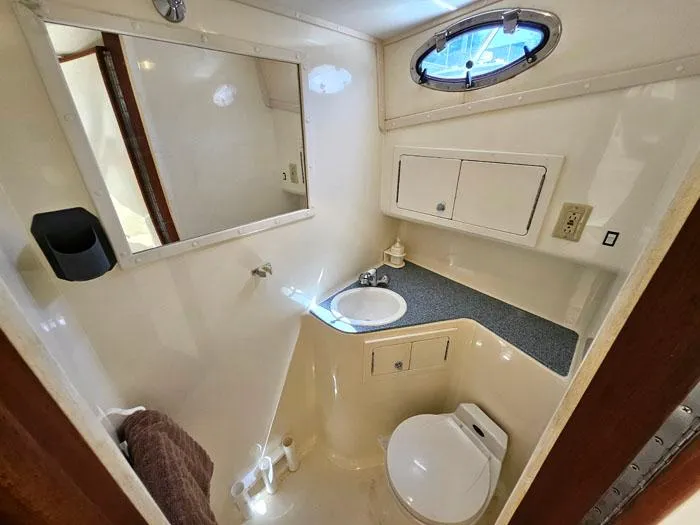  Yacht Photos Pics Compact bathroom in 2001 Carolina Classic Express 35 boat, featuring sink, toilet, and storage.