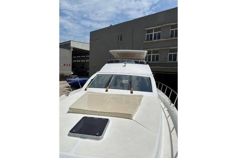  Yacht Photos Pics Modern Lanzarote 7702 yacht, 2025 model, docked near industrial buildings under a clear sky.