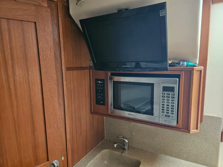  Yacht Photos Pics 2008 Albemarle 31 interior with TV, microwave, and wooden cabinetry.