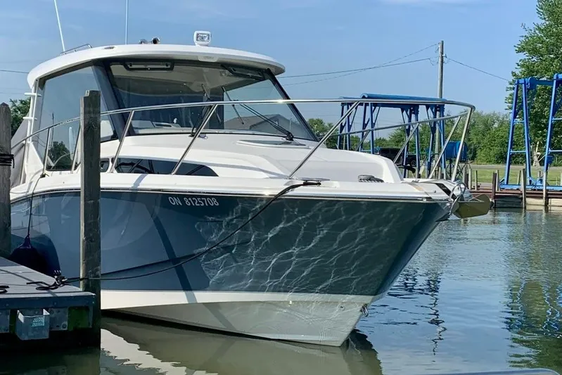  Yacht Photos Pics 2022 Boston Whaler 325 Conquest boat docked in a marina, reflecting on calm water.