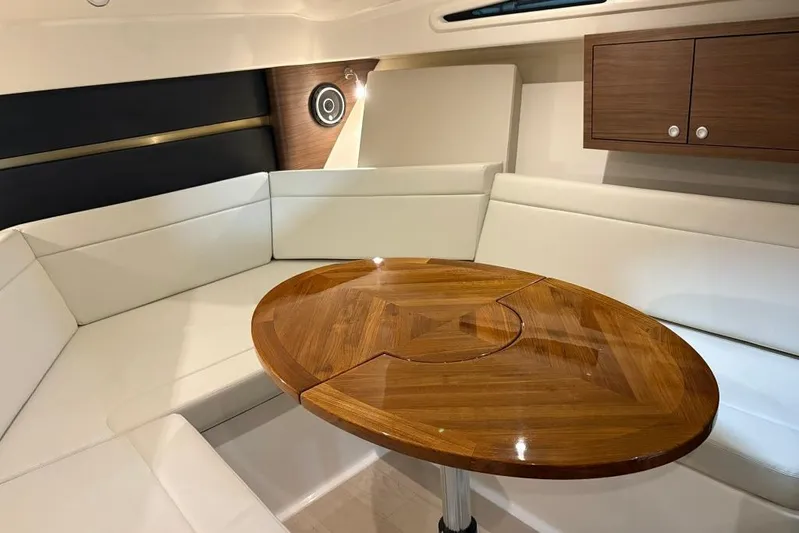  Yacht Photos Pics Interior of 2022 Boston Whaler 325 Conquest with white seating and wooden table.