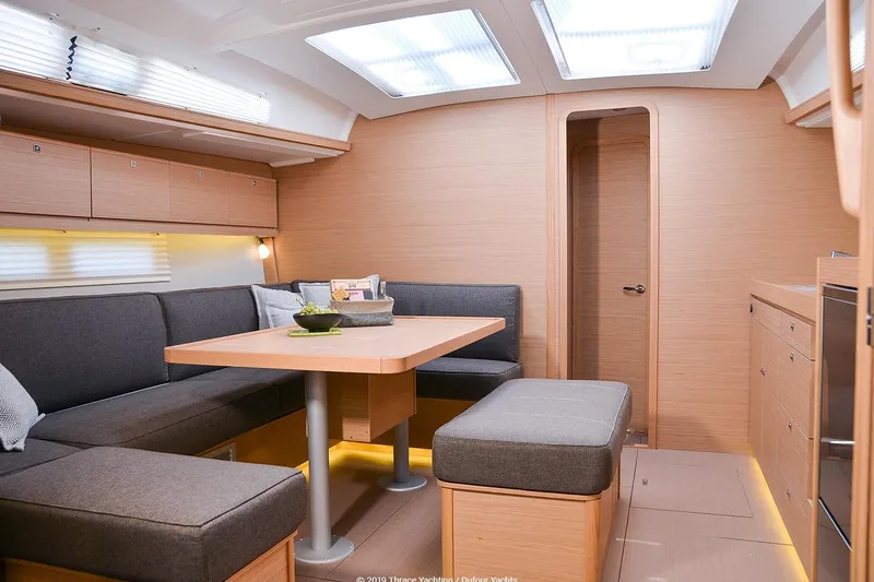  Yacht Photos Pics Modern interior of 2019 Dufour 460 Grand Large yacht with cozy seating and dining area.