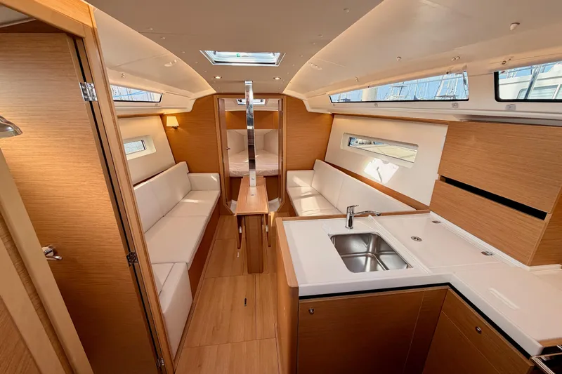 C'est Chic Yacht Photos Pics Luxurious interior of 2025 Jeanneau Sun Odyssey 350 sailboat, featuring modern kitchen and seating.