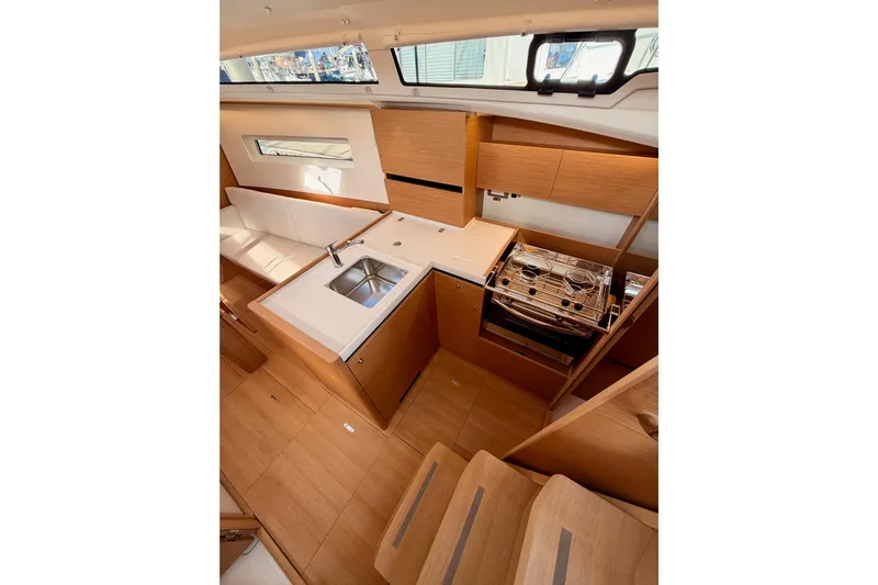 C'est Chic Yacht Photos Pics Modern kitchen interior of 2025 Jeanneau Sun Odyssey 350 yacht, featuring wood cabinetry and compact design.