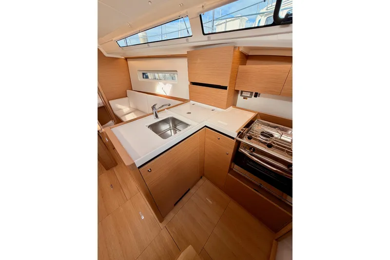 C'est Chic Yacht Photos Pics Modern kitchen interior of 2025 Jeanneau Sun Odyssey 350 yacht, featuring sleek wood cabinetry.