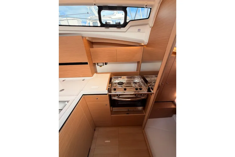 C'est Chic Yacht Photos Pics Modern kitchen interior of 2025 Jeanneau Sun Odyssey 350 yacht, featuring sleek wood cabinetry.