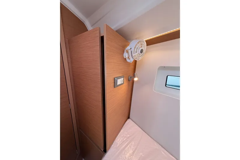 C'est Chic Yacht Photos Pics Interior cabin of 2025 Jeanneau Sun Odyssey 350, featuring wood paneling and a small window.