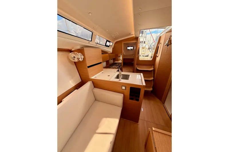 C'est Chic Yacht Photos Pics Interior of 2025 Jeanneau Sun Odyssey 350 sailboat, featuring modern wood finish and compact kitchen.
