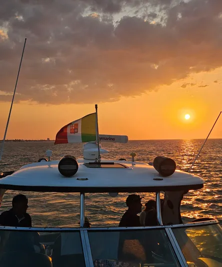 Marcello Yacht Photos Pics 2008 Sea Ray Sundancer at sunset with flag, silhouetted against ocean horizon.