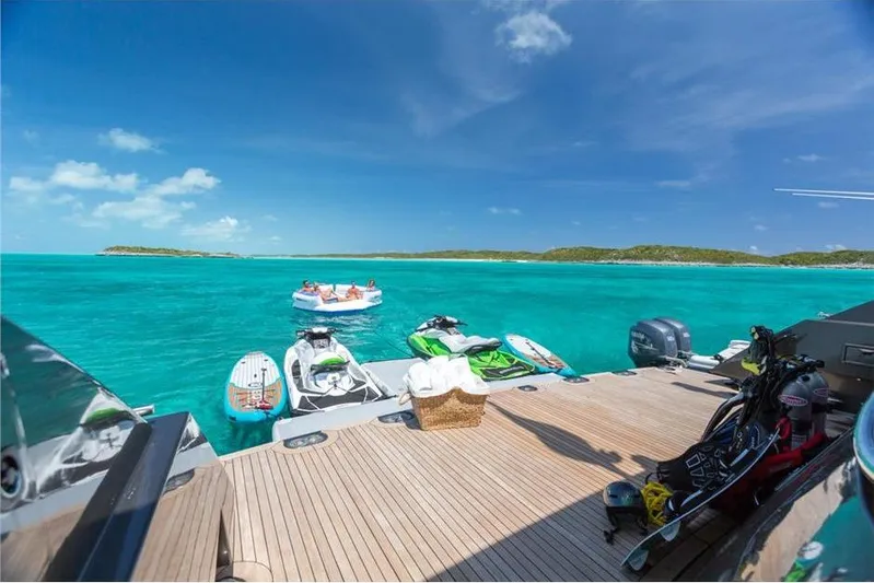 Unbridled Yacht Photos Pics Luxurious Crescent 116 yacht deck with jet skis, turquoise sea, and distant islands, 1995 model.