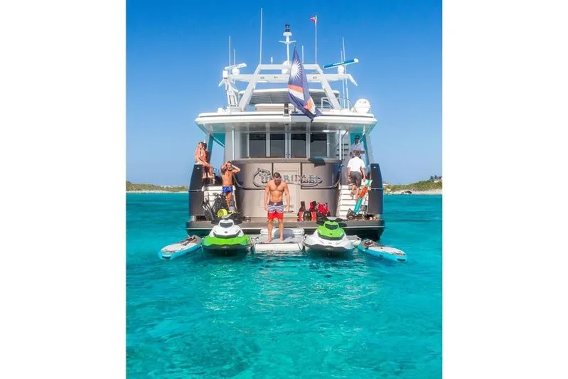 Unbridled Yacht Photos Pics People enjoying water activities on a Crescent 116 yacht, 1995 model, in clear blue sea.