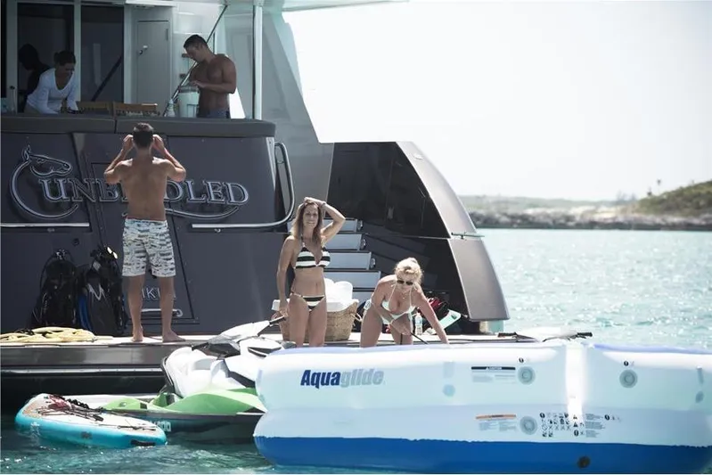 Unbridled Yacht Photos Pics People enjoying a day on a Crescent 116 yacht, with water activities nearby.