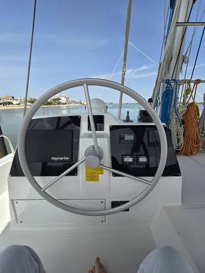 Catacha Yacht Photos Pics Steering wheel of a 2022 Bali 4.6 catamaran with navigation instruments, docked in a marina.