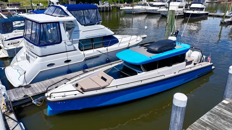 Good Vibes Yacht Photos Pics 2023 Axopar 37 Cross Cabin boat docked in a marina, featuring a sleek blue design.