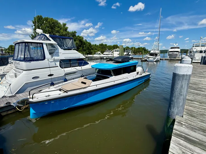 Good Vibes Yacht Photos Pics 2023 Axopar 37 Cross Cabin boat docked in a marina under a clear blue sky.