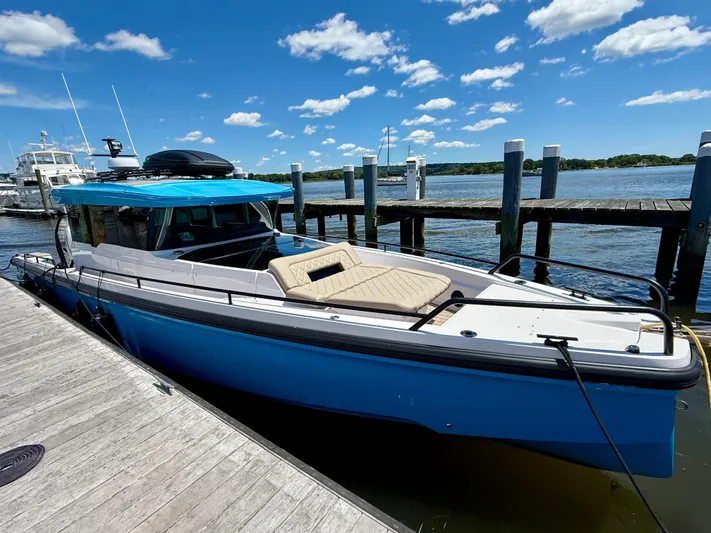 Good Vibes Yacht Photos Pics 2023 Axopar 37 Cross Cabin boat docked by a pier under a clear blue sky.