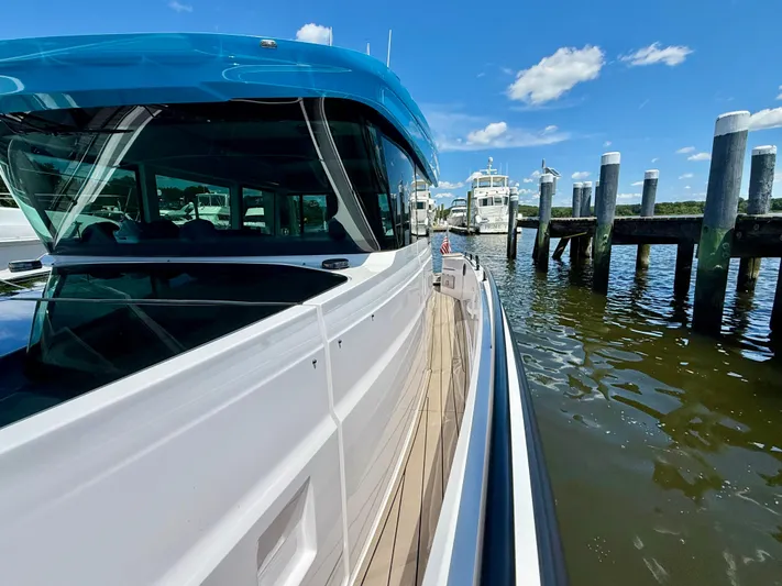 Good Vibes Yacht Photos Pics 2023 Axopar 37 Cross Cabin boat docked by wooden piers under a clear blue sky.