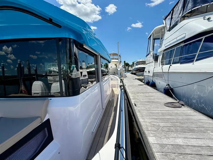 Good Vibes Yacht Photos Pics 2023 Axopar 37 Cross Cabin docked beside other boats under a clear blue sky.