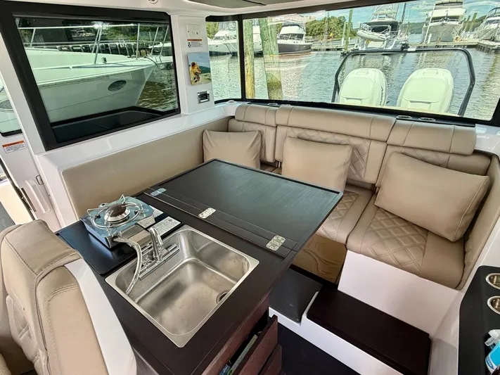 Good Vibes Yacht Photos Pics Interior of 2023 Axopar 37 Cross Cabin with seating, table, and kitchenette.