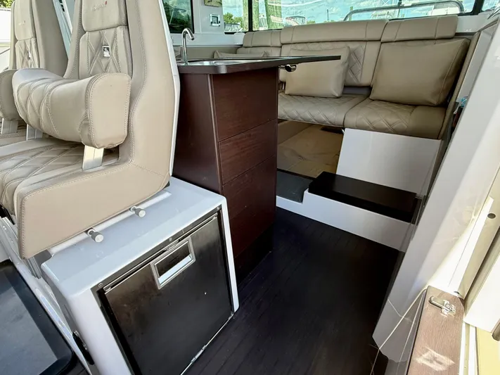 Good Vibes Yacht Photos Pics 2023 Axopar 37 Cross Cabin interior with beige seating and compact kitchenette.