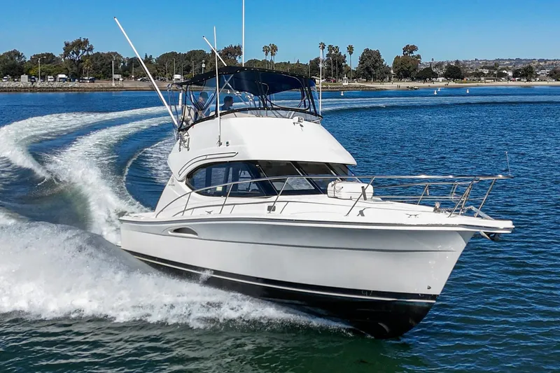 Lil' Breezy Yacht Photos Pics 2006 Riviera 33 Flybridge cruising on a sunny day in open water.