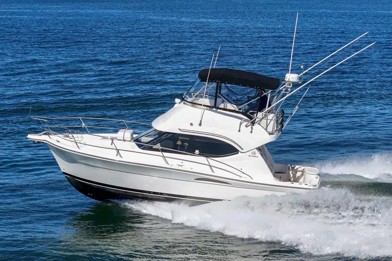 Lil' Breezy Yacht Photos Pics 2006 Riviera 33 Flybridge cruising on open water, showcasing sleek design and performance.