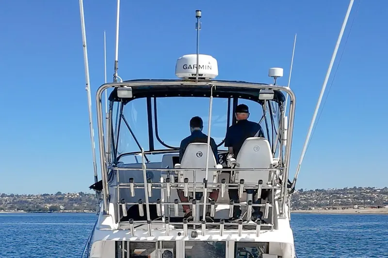 Lil' Breezy Yacht Photos Pics 2006 Riviera 33 Flybridge boat with two people navigating on a sunny day.