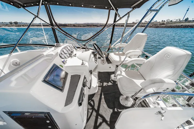 Lil' Breezy Yacht Photos Pics 2006 Riviera 33 Flybridge boat interior with helm, steering wheel, and white captain chairs.