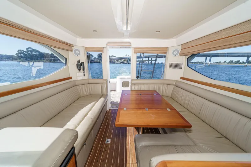 Lil' Breezy Yacht Photos Pics Interior of 2006 Riviera 33 Flybridge yacht with spacious seating and wooden table.