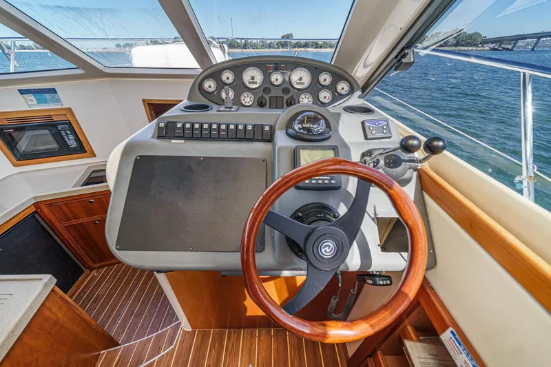 Lil' Breezy Yacht Photos Pics 2006 Riviera 33 Flybridge helm with wooden steering wheel and navigation controls.