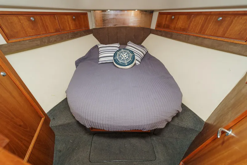 Lil' Breezy Yacht Photos Pics Cozy cabin interior of 2006 Riviera 33 Flybridge with bed and wooden storage cabinets.