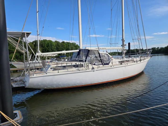 Bearaway Yacht Photos Pics 1985 Amel Maramu sailboat docked on calm water under a clear blue sky.