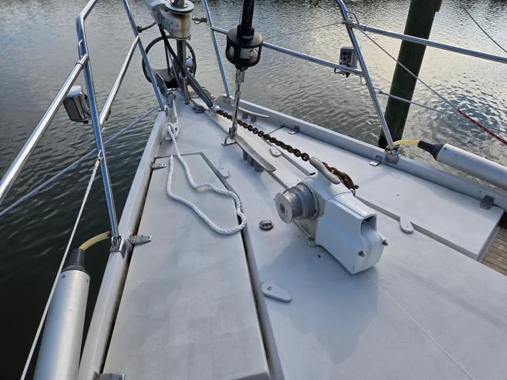 Bearaway Yacht Photos Pics Deck of 1985 Amel Maramu sailboat with anchor chain and winch, docked by calm water.