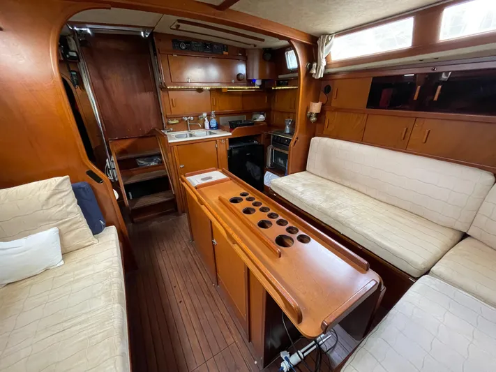 Bearaway Yacht Photos Pics Interior of 1985 Amel Maramu sailboat with wooden cabinetry and beige seating.