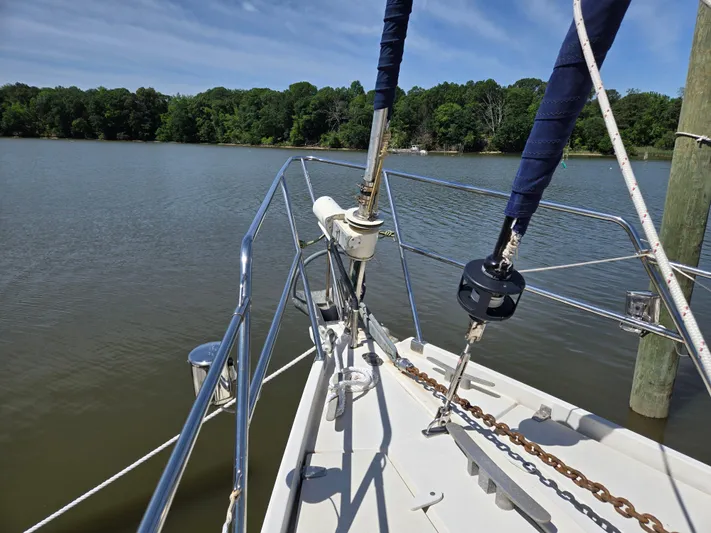 Bearaway Yacht Photos Pics Bow of 1985 Amel Maramu sailboat on calm lake with forested shoreline.