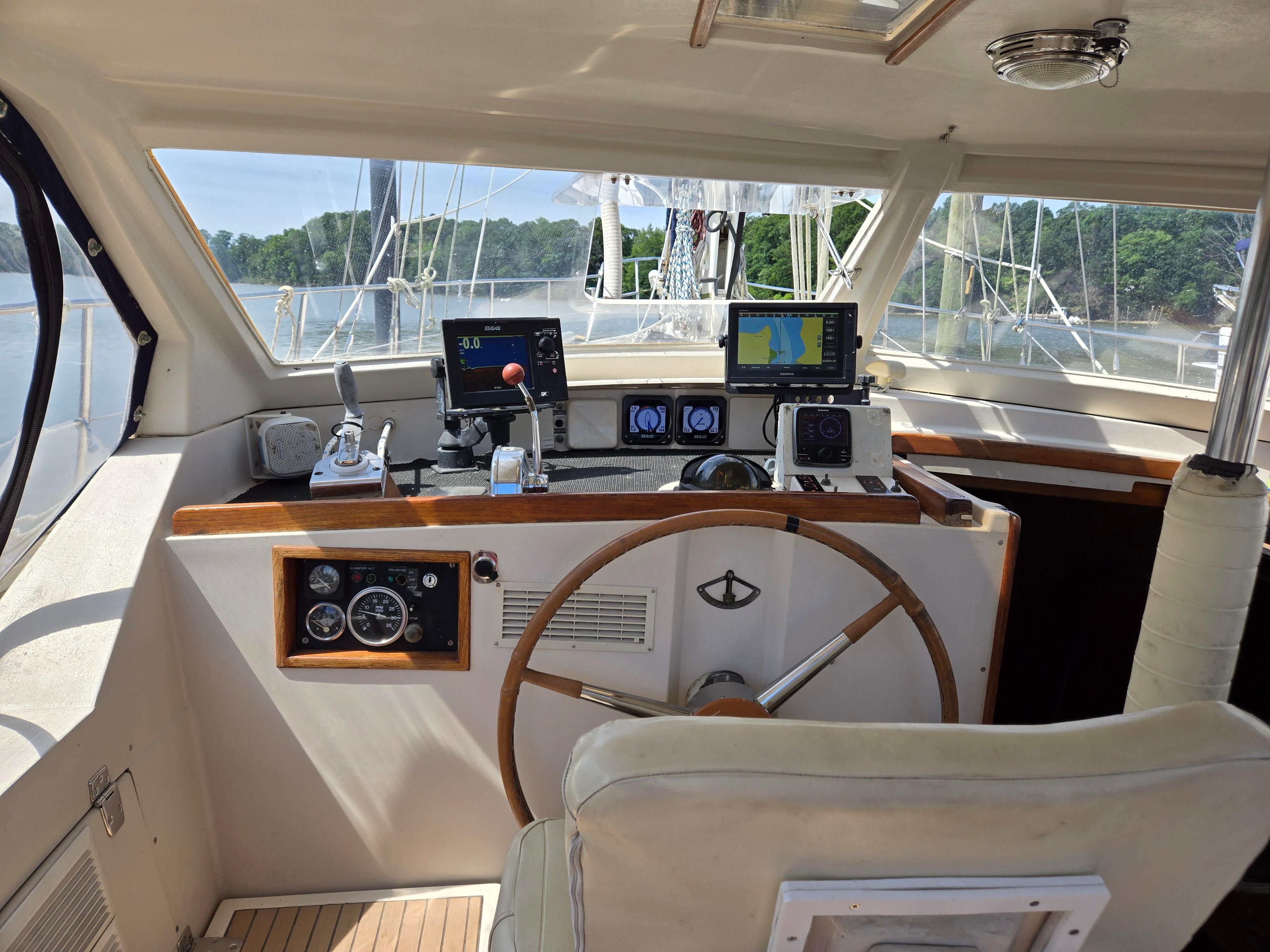 Cockpit of 1985 Amel Maramu sailboat with navigation equipment and steering wheel.