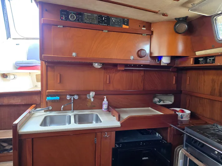 Bearaway Yacht Photos Pics 1985 Amel Maramu yacht kitchen with wooden cabinets, double sink, and stove.