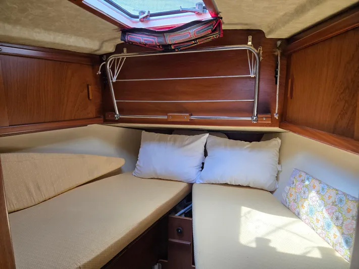Bearaway Yacht Photos Pics Cozy cabin interior of 1985 Amel Maramu sailboat with cushions and wooden paneling.