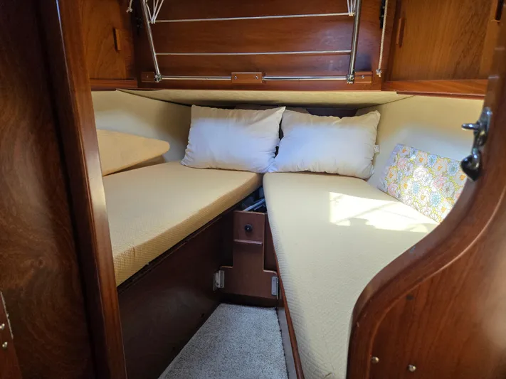 Bearaway Yacht Photos Pics Cozy cabin interior of 1985 Amel Maramu sailboat with wooden finish and cushions.
