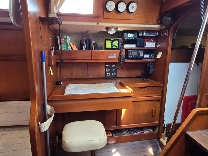 Bearaway Yacht Photos Pics Navigation station inside 1985 Amel Maramu sailboat with wooden interior and communication equipment.