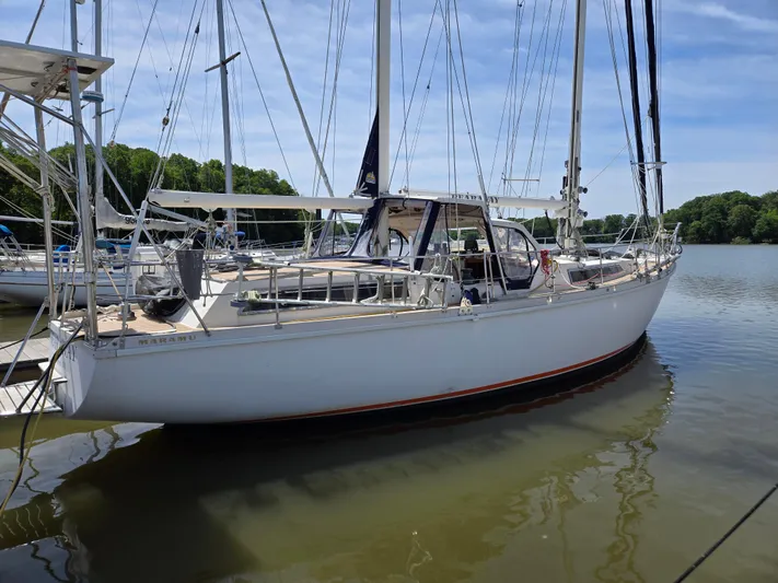 Bearaway Yacht Photos Pics 1985 Amel Maramu sailboat docked on calm water under a clear blue sky.