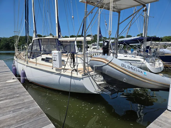 Bearaway Yacht Photos Pics 1985 Amel Maramu sailboat docked with dinghy, clear sky, calm water.
