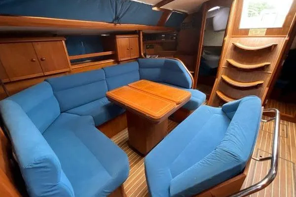 Ligera Yacht Photos Pics Interior of 2002 Jeanneau Sun Odyssey 45.2 yacht with blue seating and wooden table.